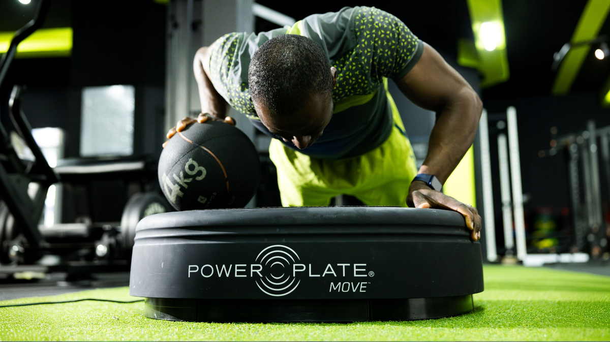 Power Plate MOVE whole body vibration platform used for medicine ball push-up exercise in athletic training facility