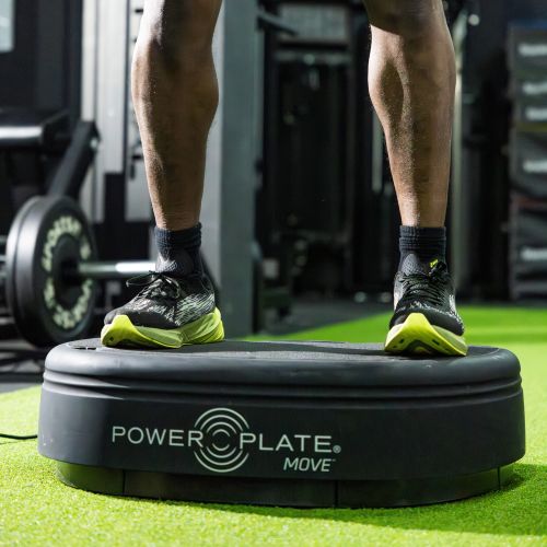 Power Plate MOVE whole body vibration platform used during standing training exercise on indoor athletic turf