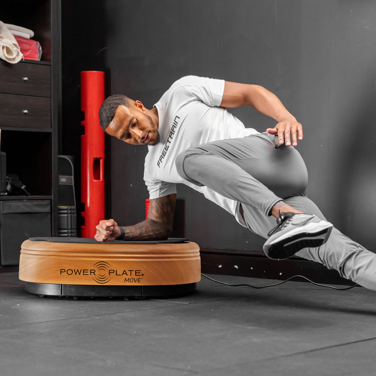 Power Plate MOVE whole body vibration platform in woodgrain finish used during supported side plank exercise