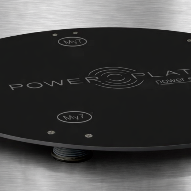 Power Plate my7 vibration platform positioned on Power Shield vibration reduction base with user standing on platform demonstrating stabilized training environment on hardwood flooring