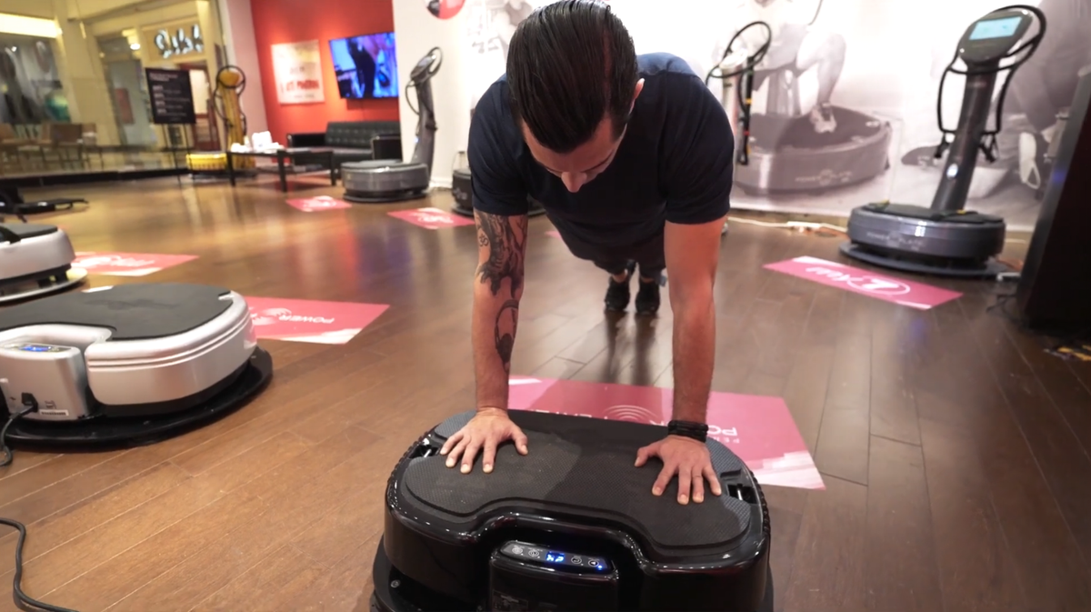 User performing push-up exercise on a Power Plate whole body vibration platform demonstrating upper body training movements performed on vibrating platforms used for strength, balance, and stability exercises.