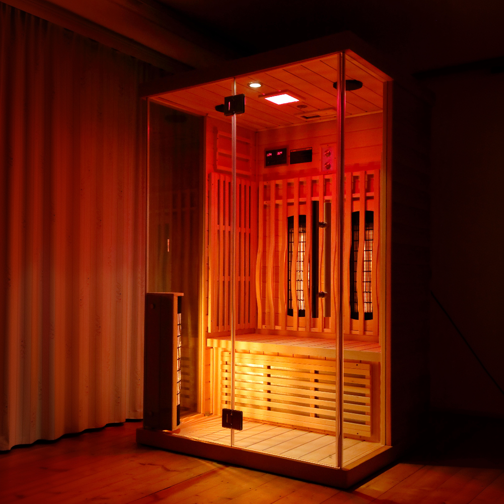 Indoor infrared sauna unit with illuminated heating panels and wood interior, illustrating infrared heat therapy and controlled thermal exposure in a wellness setting.