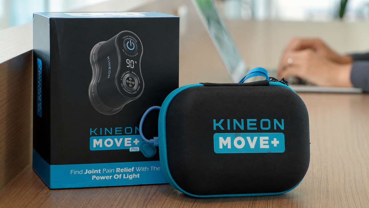 Kineon MOVE+ red light therapy device with travel case and packaging displayed on tabletop workspace