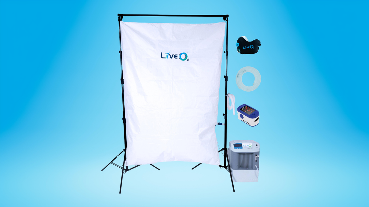 LiveO2 Adaptive Contrast EWOT system components layout showing the reservoir frame, mask, tubing, pulse oximeter, remote switch, and air separator on a blue studio background