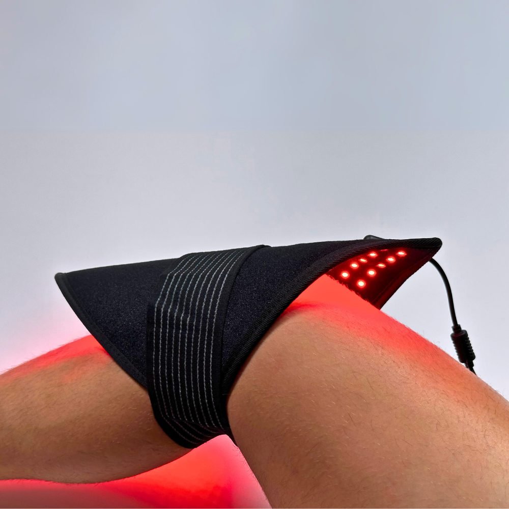 Lumara red light therapy pad secured around knee joint using strap for targeted placement in close up view