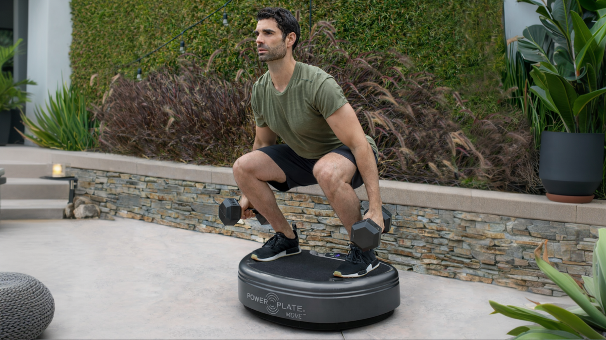 Power Plate MOVE whole body vibration platform used for weighted squat exercise in outdoor residential setting