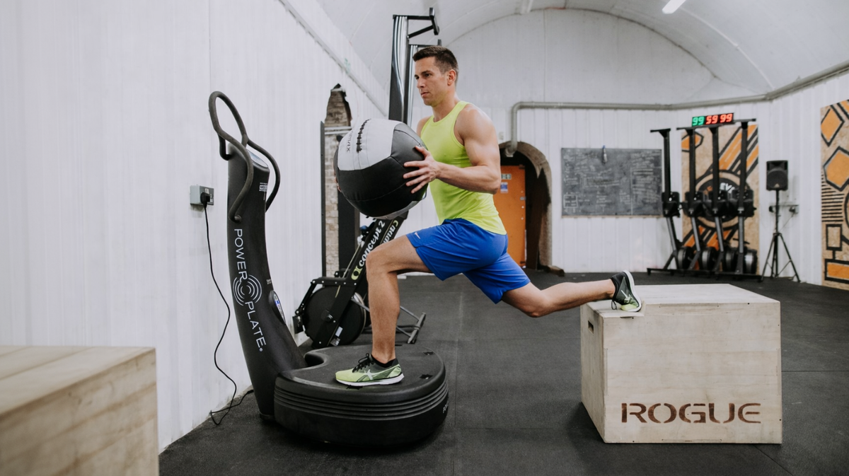 Athlete performing single-leg stability exercise on Power Plate pro5 vibration platform in gym training environment