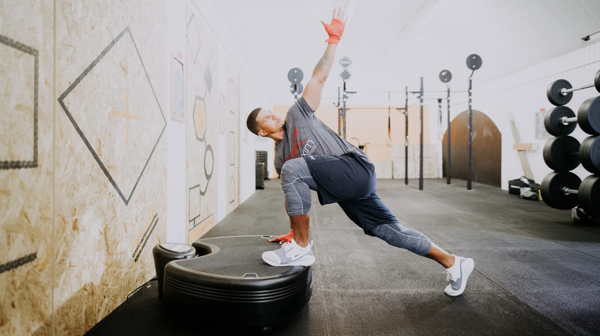 Athlete performing mobility stretch on Power Plate pro5 whole body vibration platform in athletic training facility