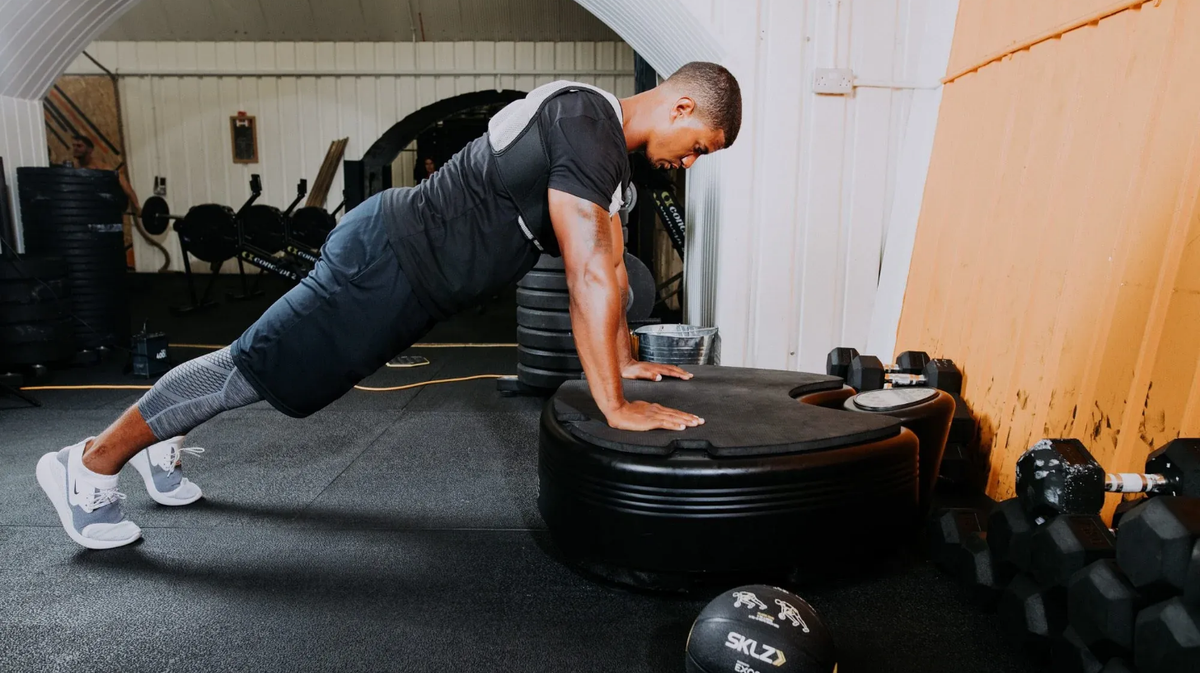 Athlete performing single-leg stability exercise on Power Plate pro5 whole body vibration platform in strength gym