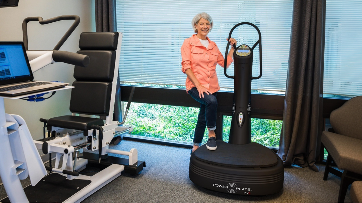 Senior user standing on Power Plate pro5 vibration platform in clinical rehabilitation setting