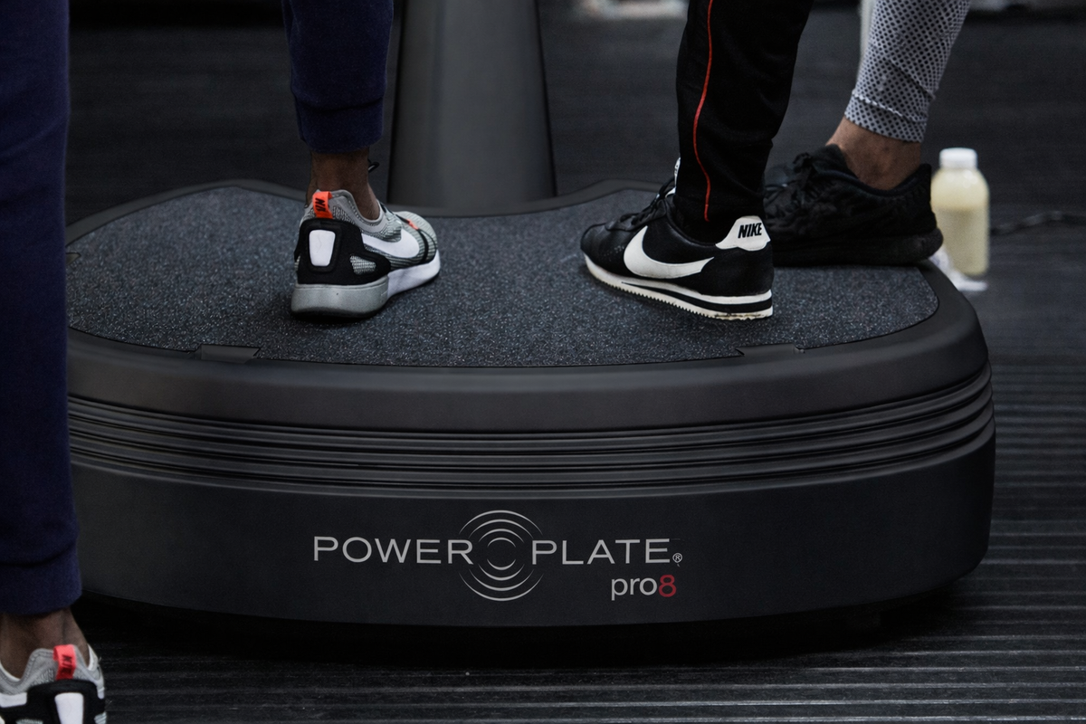 Power Plate pro8 whole body vibration platform users standing on vibration plate training surface in gym environment
